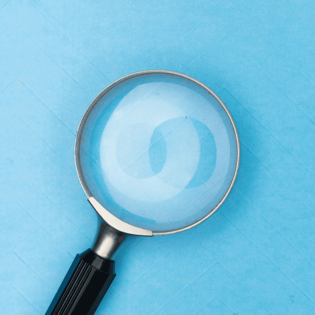quality of earnings and due diligence solutions exemplified by an image of a magnifying glass on a blue background