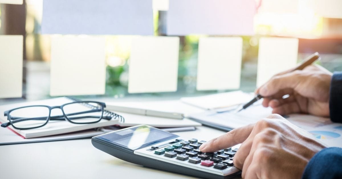 man typing on calculator working on small business budget