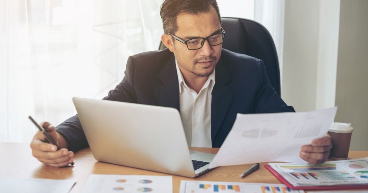 man looking at charts with computer open