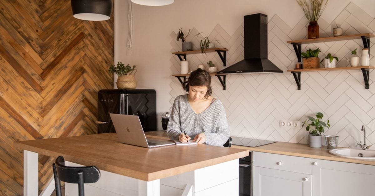 Women writing at desk with computer open