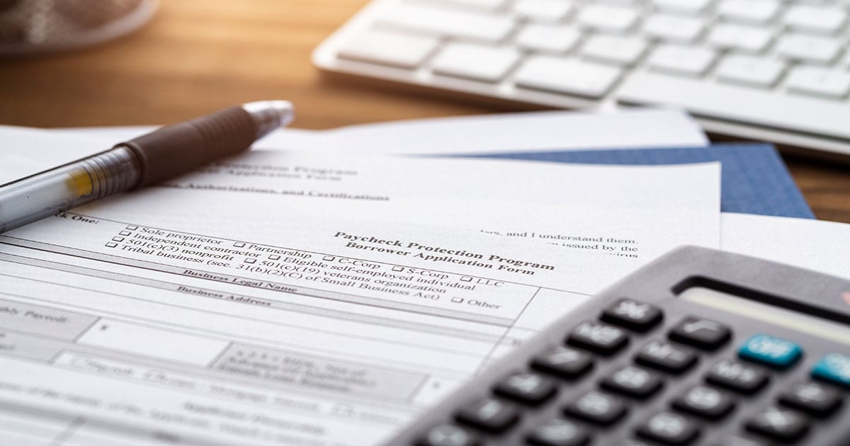 PPP Forgiveness Application with calculator pen and keyboard