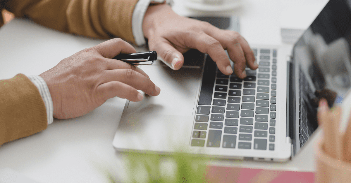 Man on computer with pen in one hand