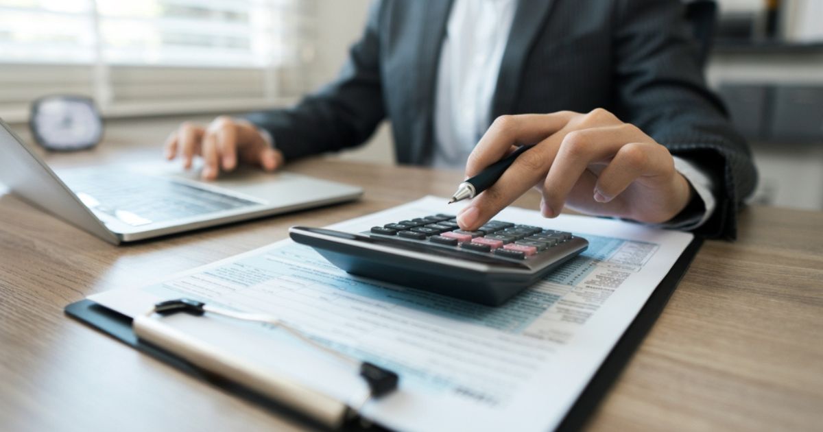 Businessman calculates taxes using calculator and laptop