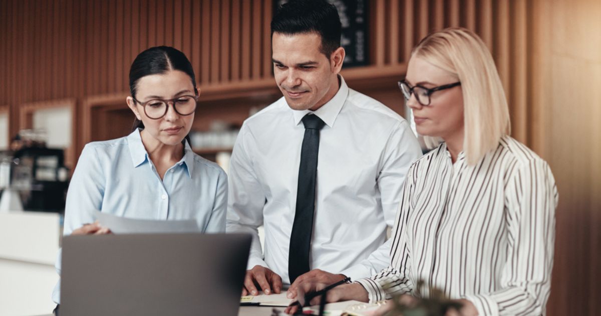 Three young businesspeople standing at a table